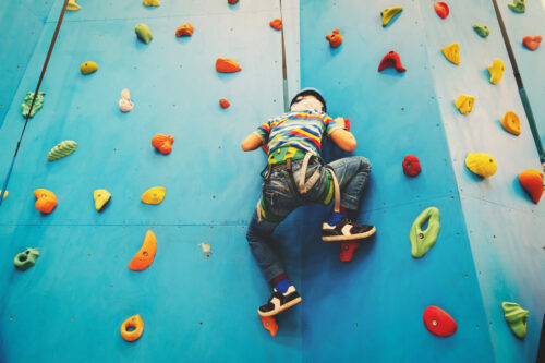 little boy climbing wall in sport center, kids sport activities