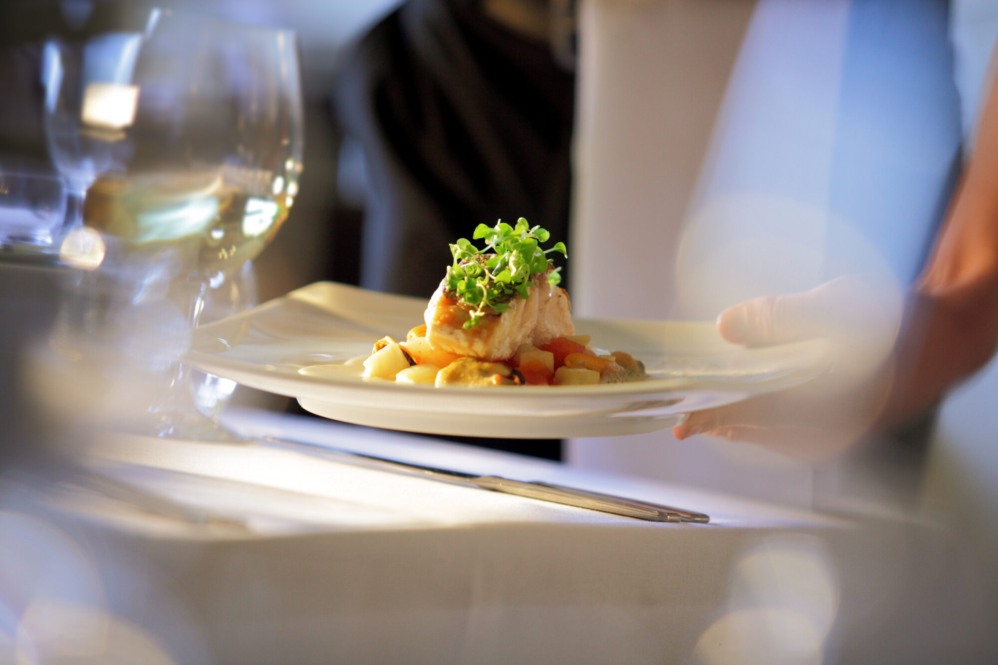 Soft focus Photo, clean, abstract, contemporary shot of waiter serving meal to a table.